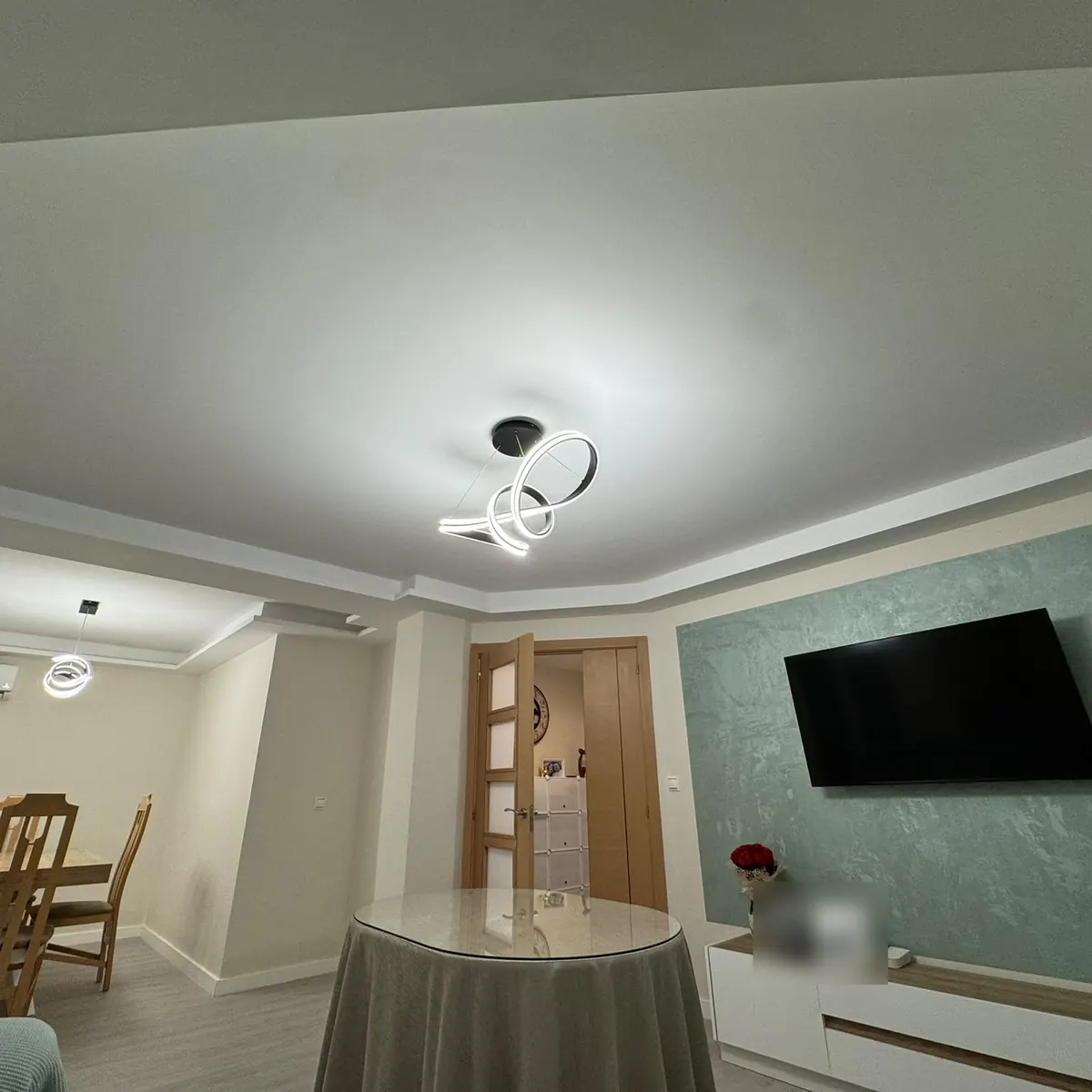 Salón reformado con techo nuevo iluminado y pared de micrometal verde